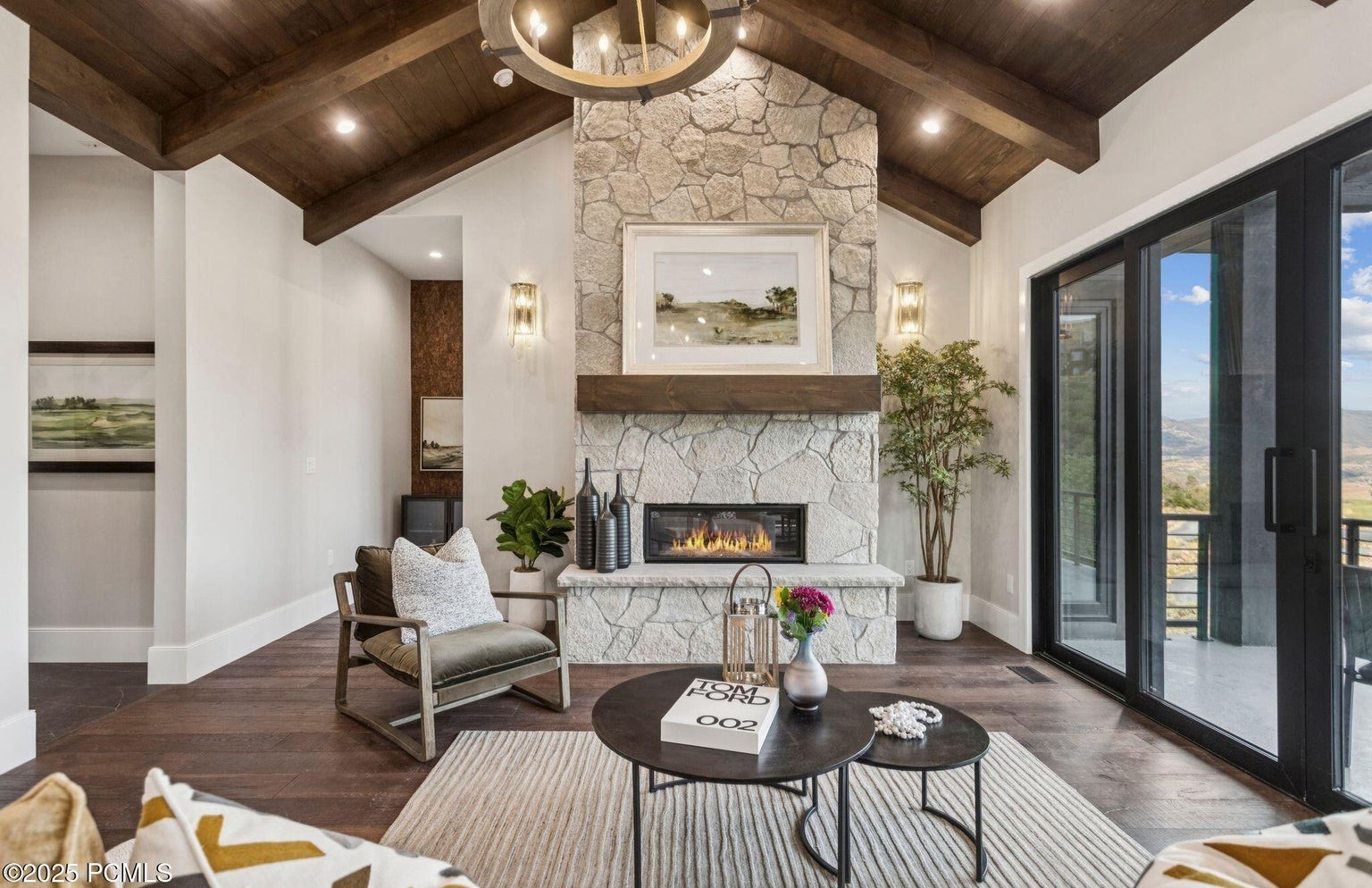 Living room with stone fireplace and floor-to-ceiling mountain views