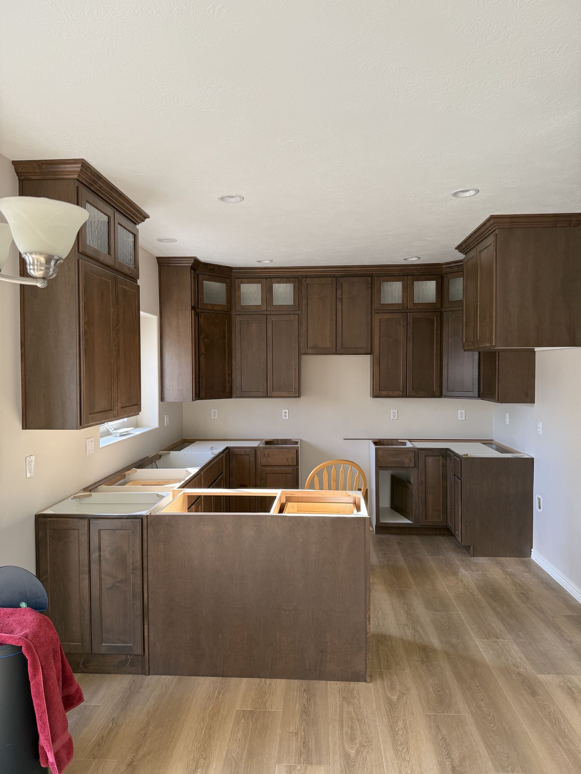 New kitchen cabinets installed with crown molding and glass upper panels — awaiting countertops