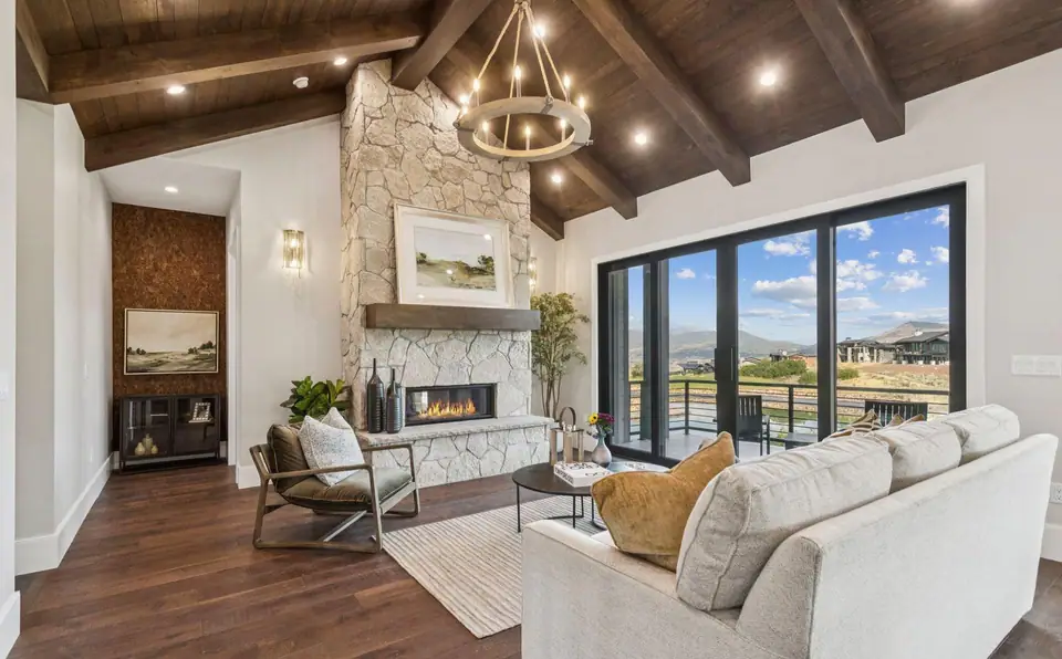 Three Peak Construction custom home interior — vaulted wood beam ceiling, stone fireplace, and mountain views in Hideout, Utah
