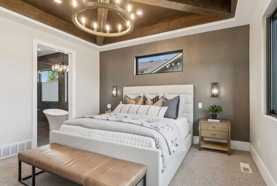Master bedroom with wood beam tray ceiling, chandelier, and en-suite bath visible