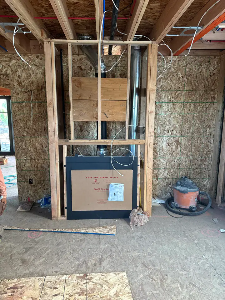 864CF gas fireplace unit being installed in framed chase, double-wall chimney pipe, proper clearances maintained, living room taking shape