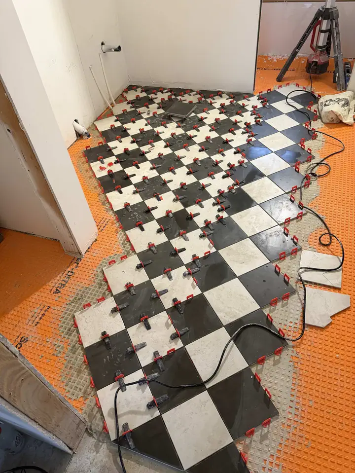 Black and white checkerboard tile being set on an orange uncoupling membrane