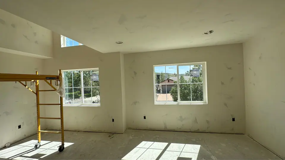 Drywalled bedroom with two windows in the new addition