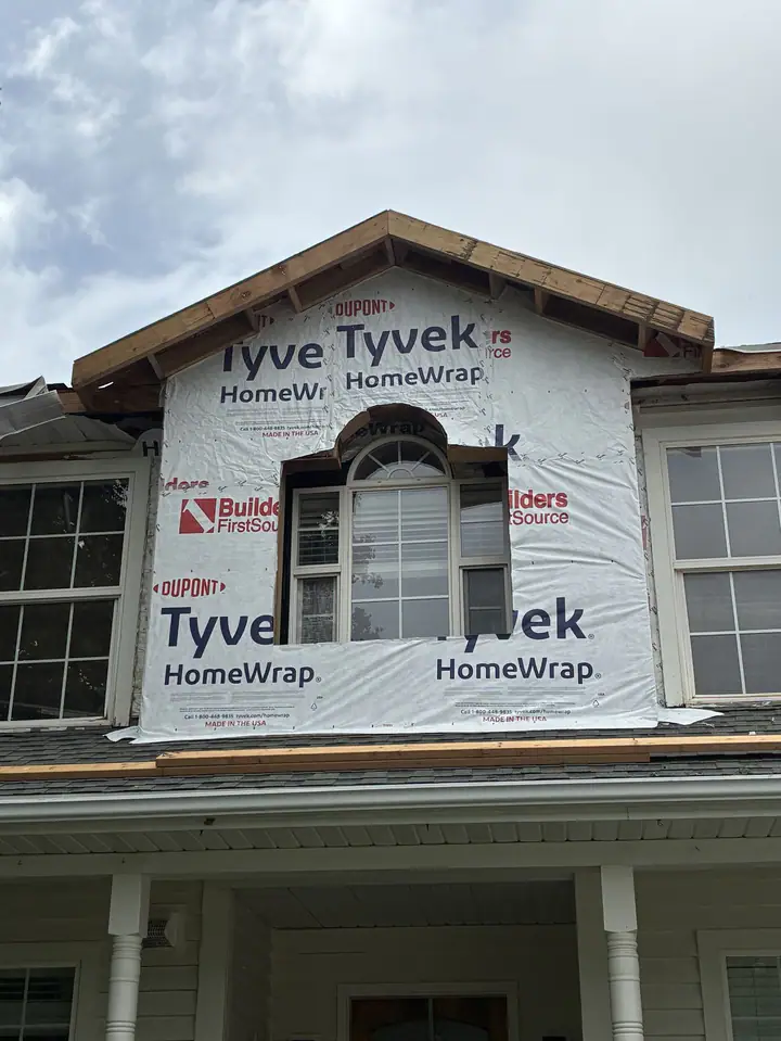 New second-story gable with an arched window, wrapped in house wrap
