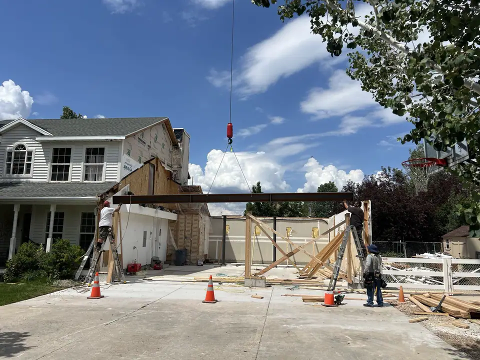 Crane setting a steel beam over the new garage opening