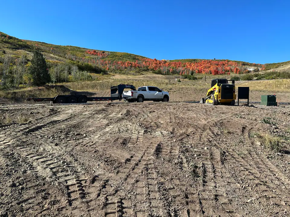 Raw mountain building lot with scrub oak, dirt, and construction equipment, Day 1 of the Park City Parade Home project