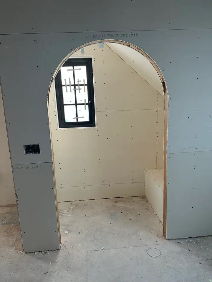 Custom arched alcove with drywall being finished, showing the precision of the framing and the craftsmanship in curved details