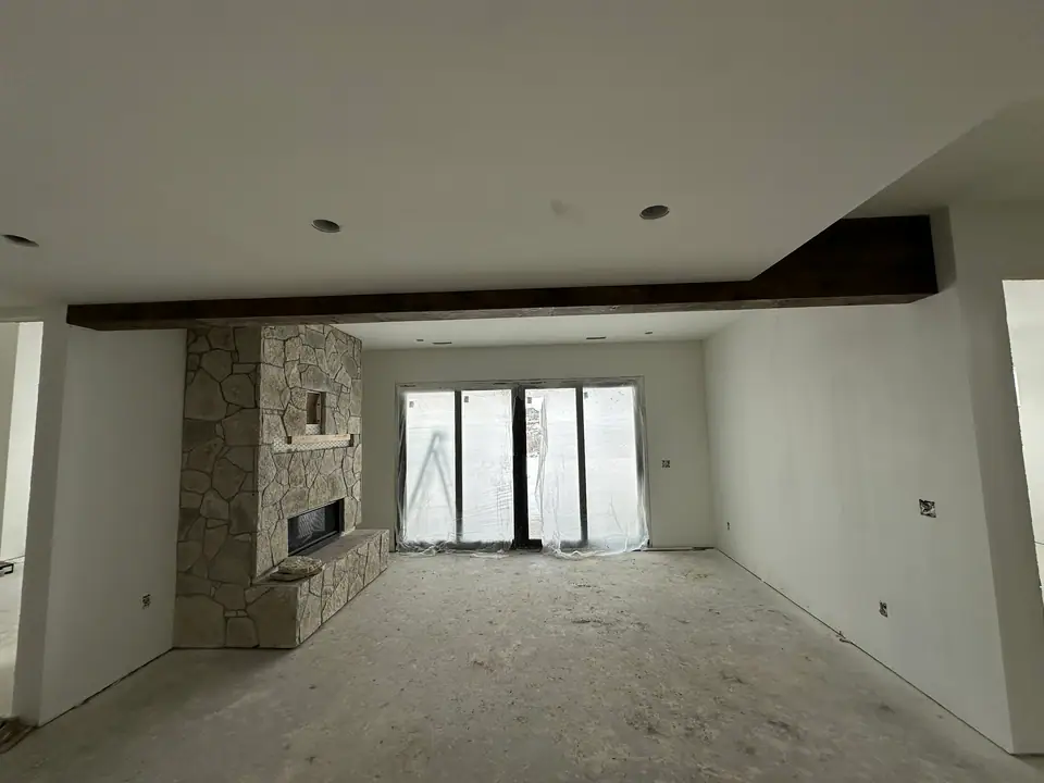 Great room during pre-finish phase, drywall, rough openings, and exposed ceiling structure