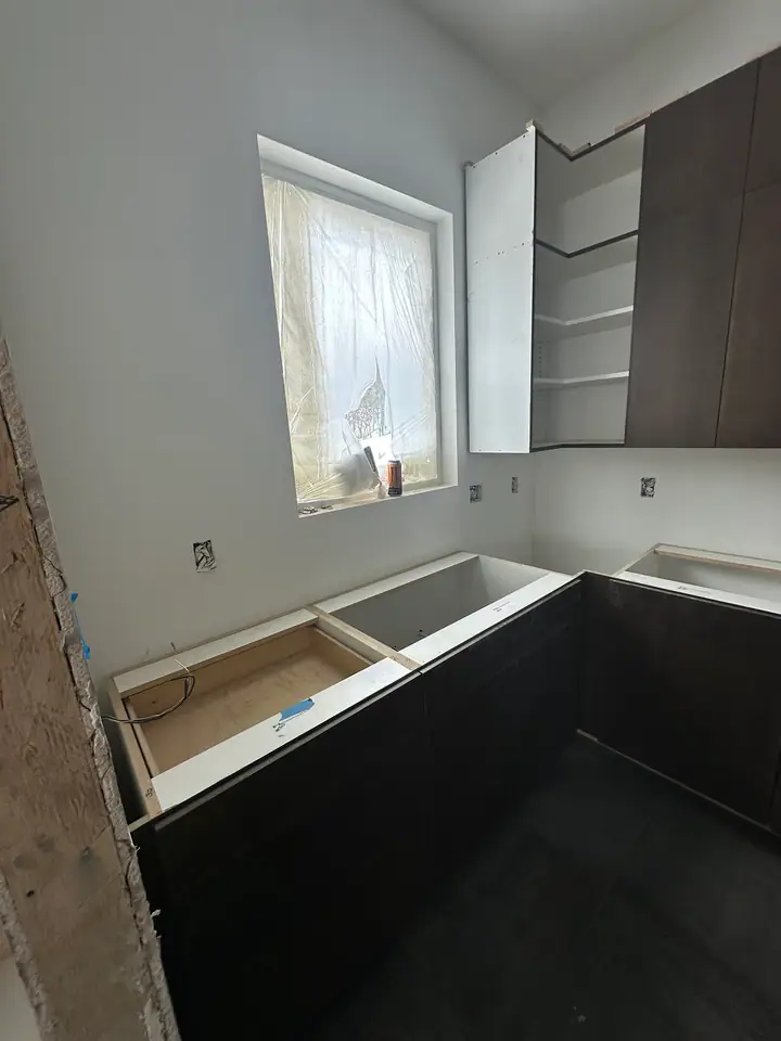Bathroom vanity cabinets installed awaiting countertops, tile work in progress