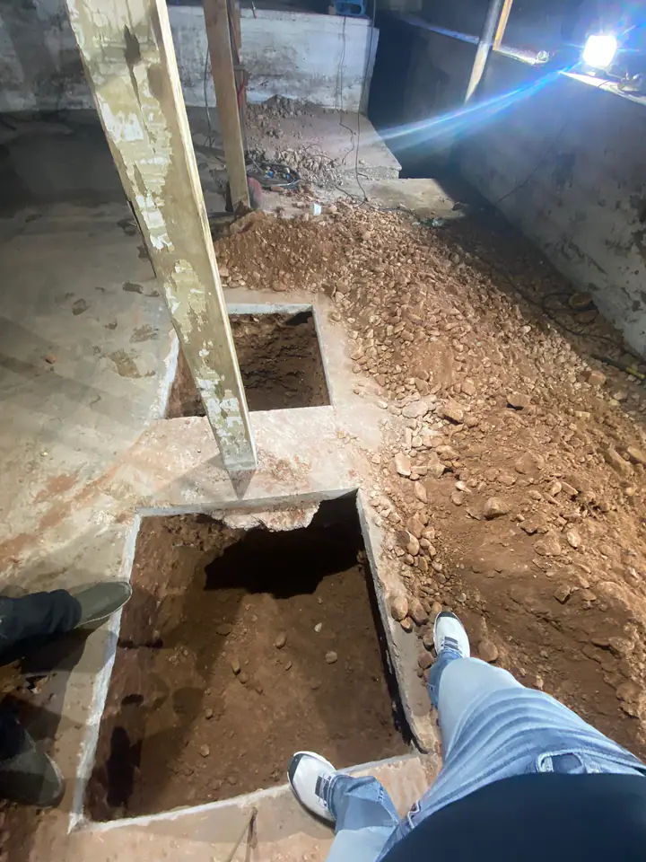 Footing excavation pits viewed from above, concrete slab cut in sections around existing columns for foundation underpinning