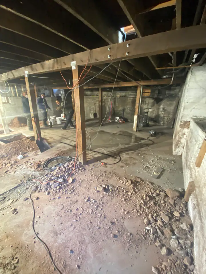 New steel I-beam installed across basement ceiling, supported by engineered columns on new footings, structural upgrade from wood to steel