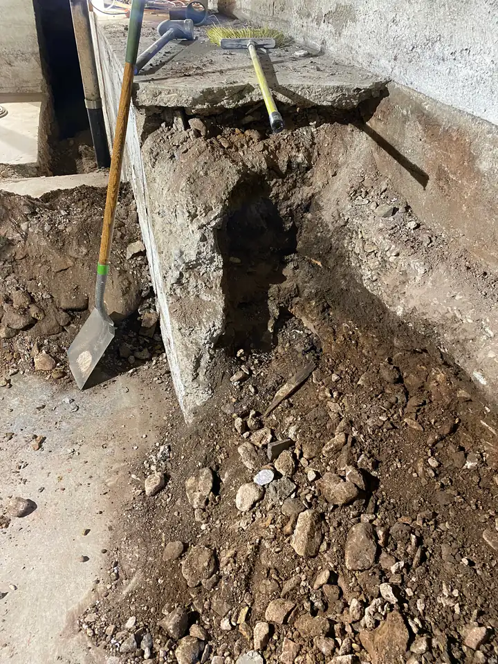Undermined foundation footing with exposed soil beneath, structural failure in progress