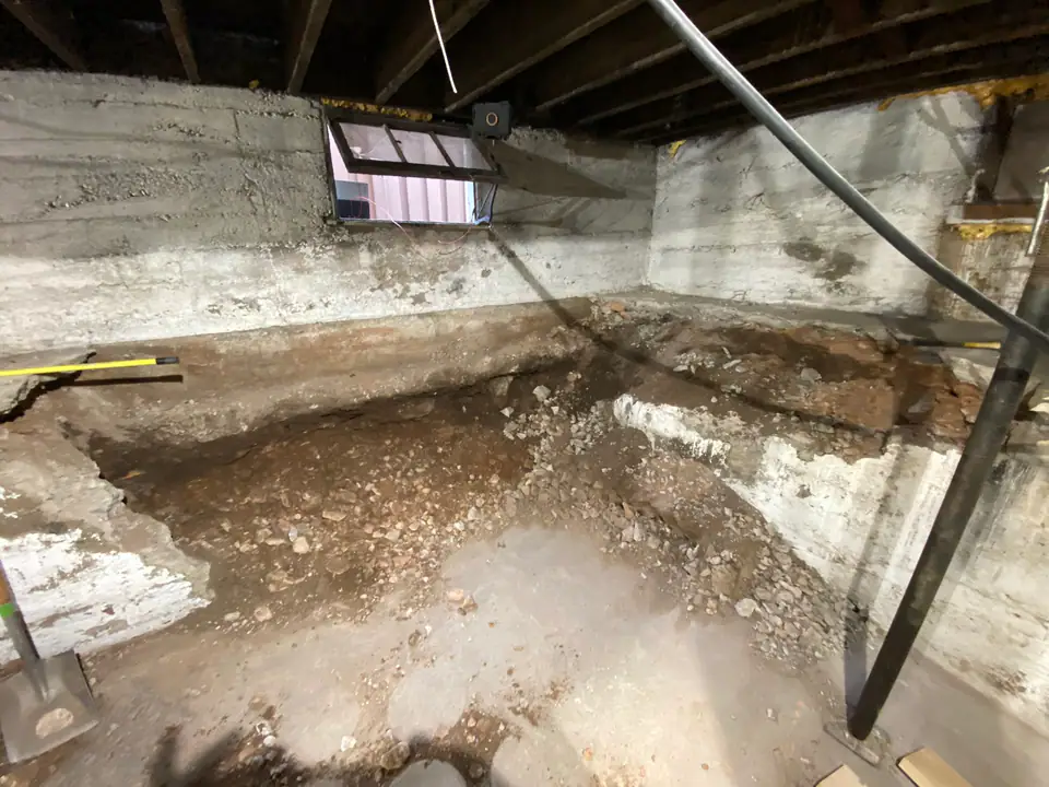 Original basement crawlspace with failing foundation, exposed dirt, temporary supports, crumbling concrete walls