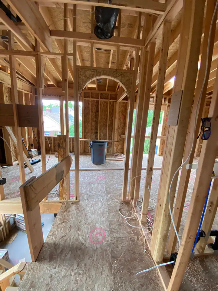Interior framing with PEX plumbing rough-in visible, red and blue supply lines running through studs, ABS drain pipe, electrical boxes mounted