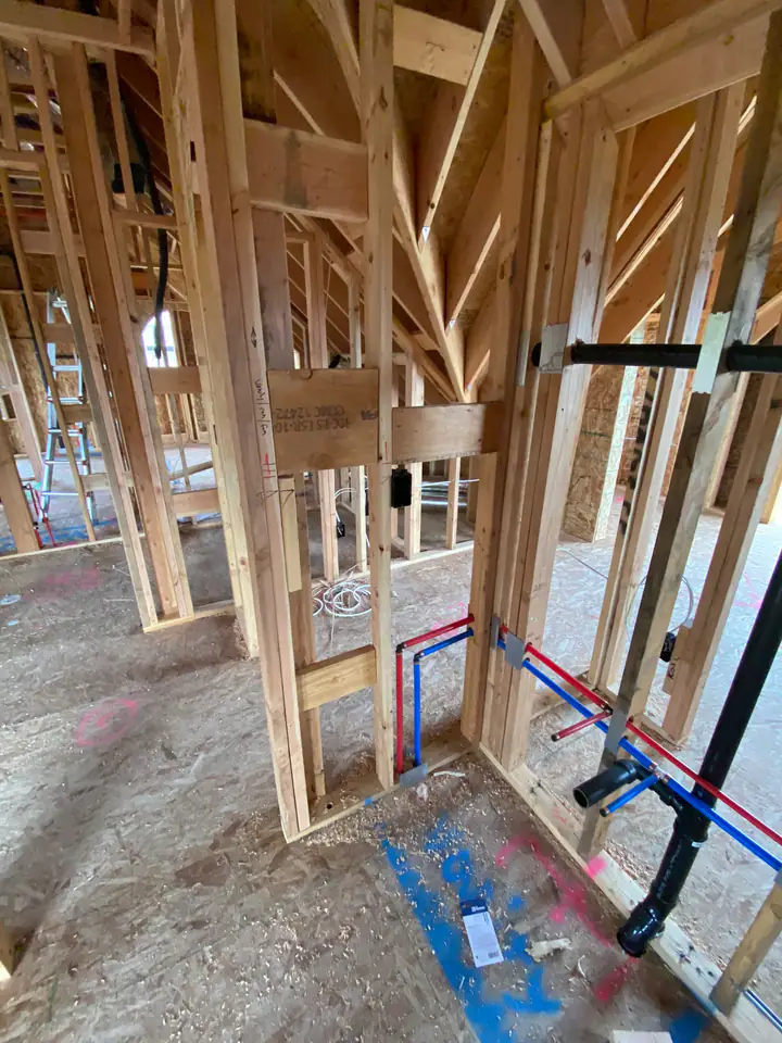 Wide angle of interior framing showing complete MEP rough-in, plumbing, electrical wiring, and HVAC ductwork all visible in open walls