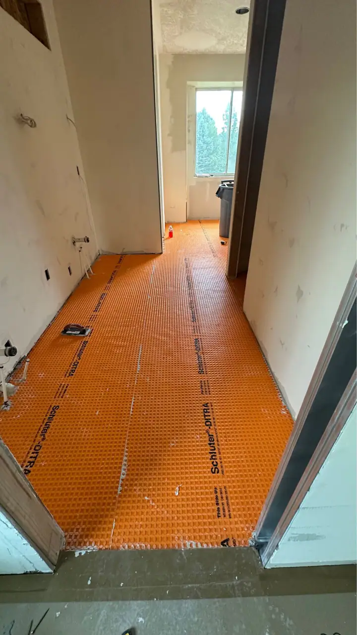 Orange waterproof uncoupling membrane on a bathroom floor before tile
