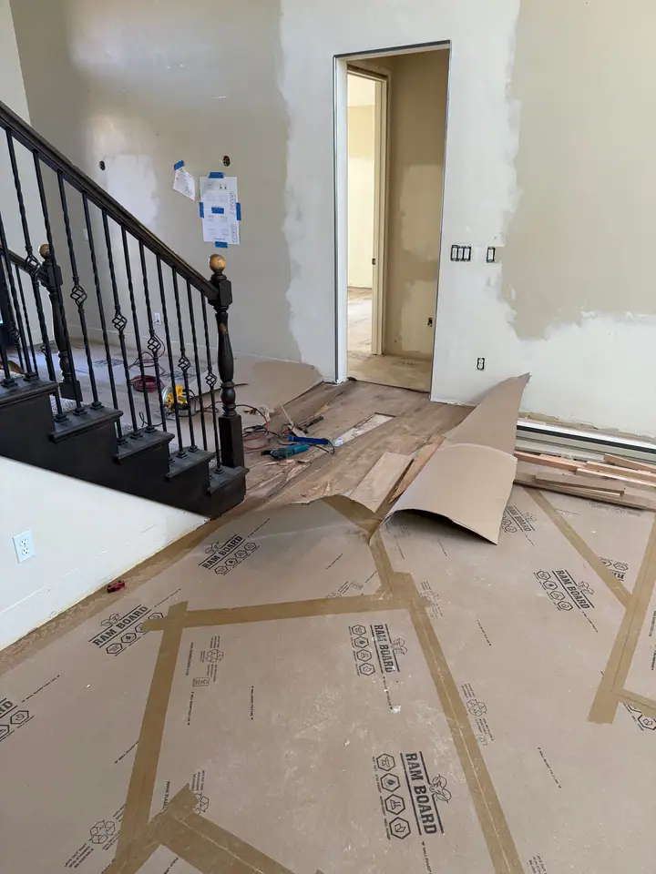 Great room stripped to subfloor with the stair railing in place