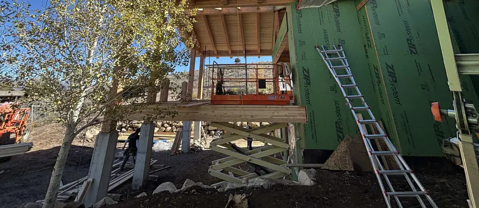 Addition framing beside the existing house with a lift and ladder
