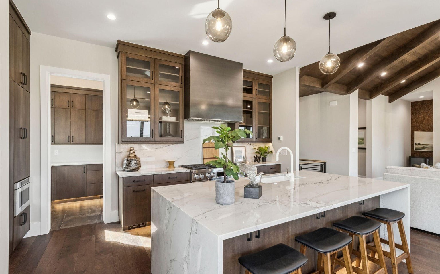 Kitchen with waterfall marble island and dark cabinetry